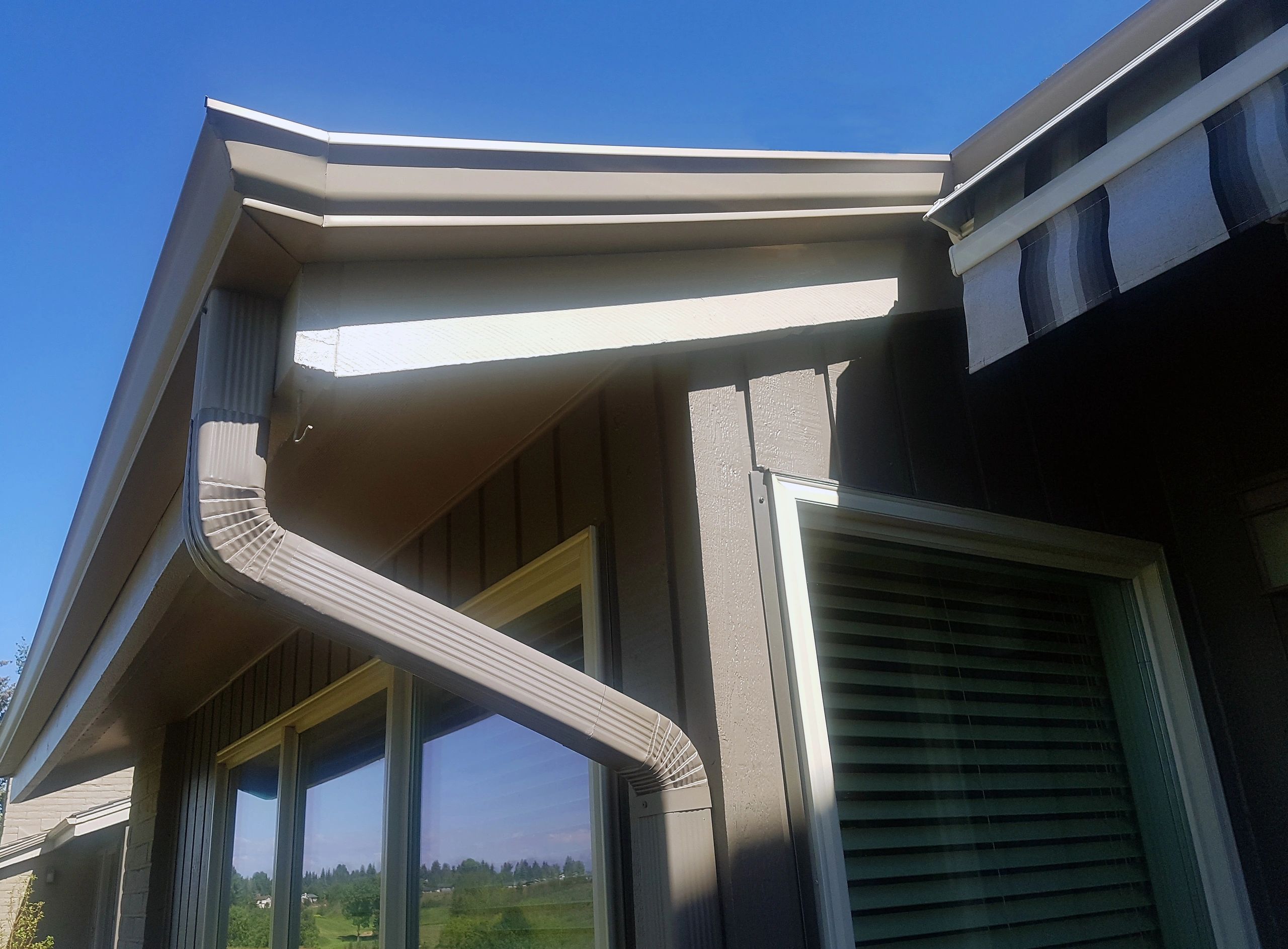 Close-up of a residential gutter and downspout along the roofline